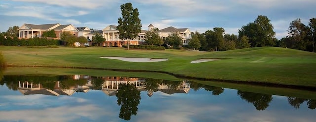 view of home's community featuring a yard, a water view, and view of golf course