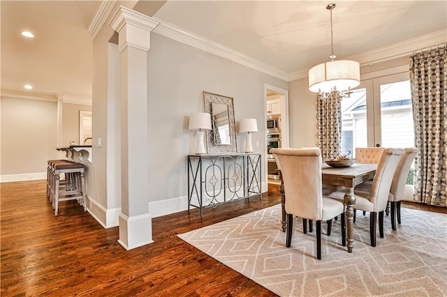 dining room with wood finished floors, recessed lighting, crown molding, decorative columns, and baseboards