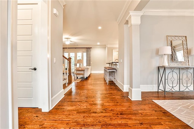 hall featuring wood finished floors, recessed lighting, crown molding, decorative columns, and baseboards