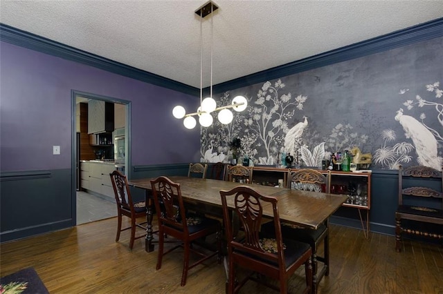 dining area featuring wood finished floors, a textured ceiling, crown molding, and an inviting chandelier