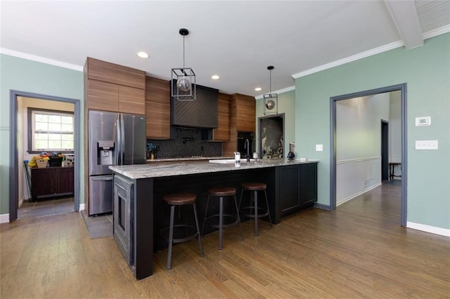 kitchen featuring wood finished floors, a breakfast bar area, pendant lighting, backsplash, and stainless steel refrigerator with ice dispenser