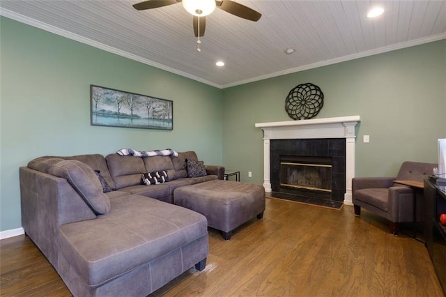 living room featuring a ceiling fan, crown molding, wood finished floors, a tiled fireplace, and recessed lighting