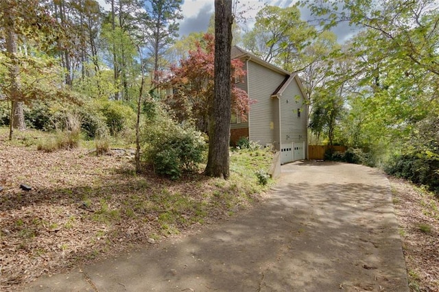 view of property exterior with an attached garage and concrete driveway