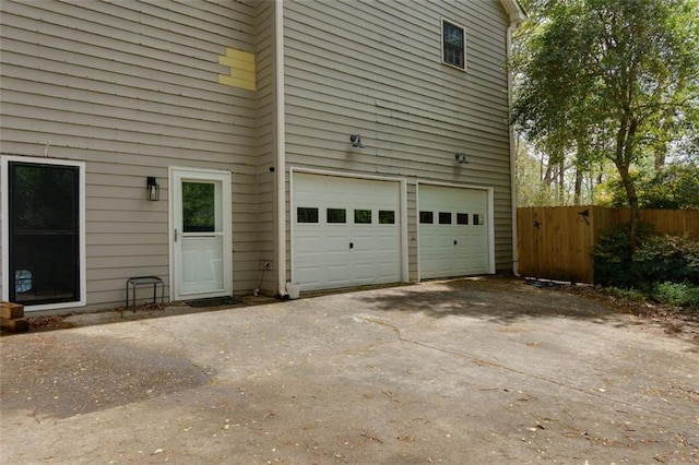 garage featuring aphalt driveway and fence
