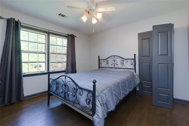 bedroom featuring baseboards, wood finished floors, visible vents, and ceiling fan