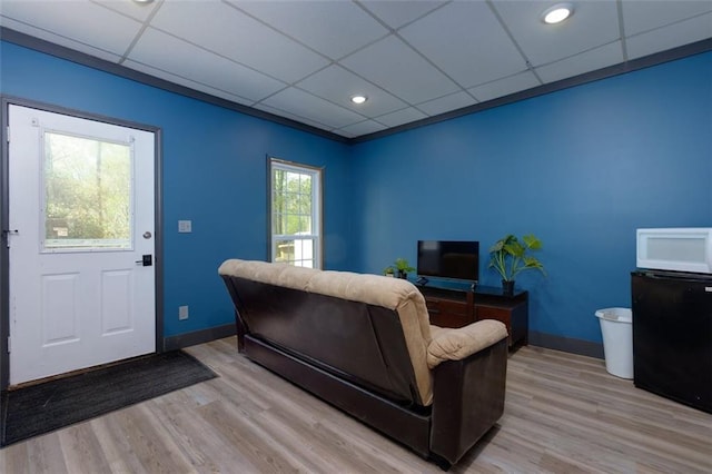 living room with a paneled ceiling, light wood finished floors, and baseboards