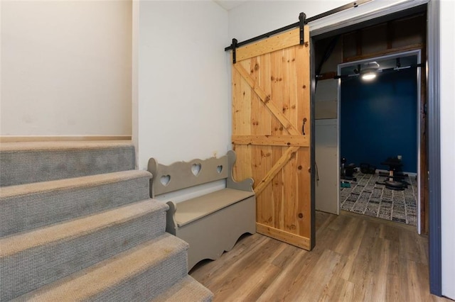 staircase featuring a barn door and wood finished floors