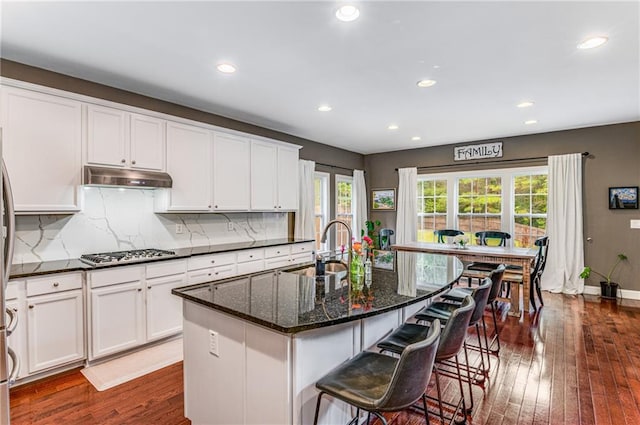 kitchen featuring dark wood-type flooring, a healthy amount of sunlight, sink, and a center island with sink