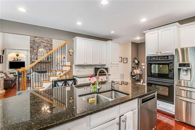 kitchen featuring dark hardwood / wood-style floors, stainless steel appliances, dark stone countertops, sink, and white cabinets