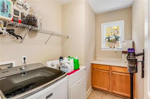 washroom with cabinets, washing machine and clothes dryer, and light tile patterned floors