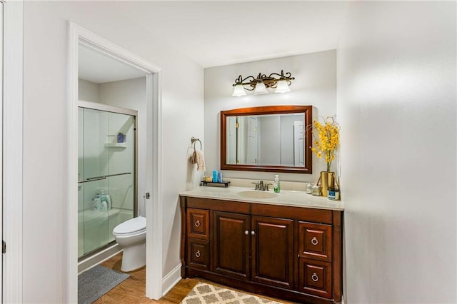 bathroom featuring vanity, toilet, hardwood / wood-style flooring, and a shower with shower door