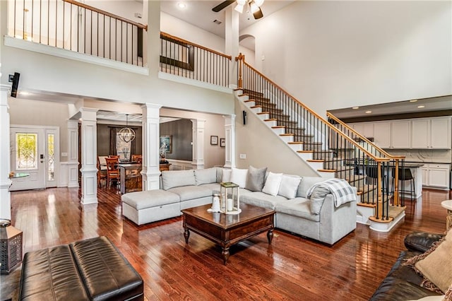 living room with decorative columns, wood-type flooring, a high ceiling, and ceiling fan