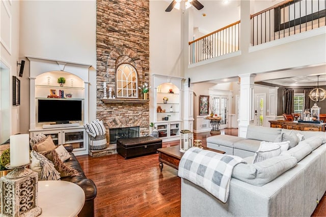 living room featuring a towering ceiling, dark hardwood / wood-style floors, ceiling fan, and decorative columns