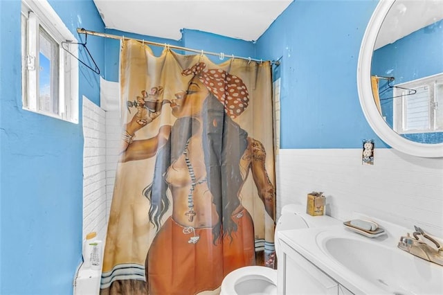 bathroom featuring toilet, vanity, walk in shower, and tile walls