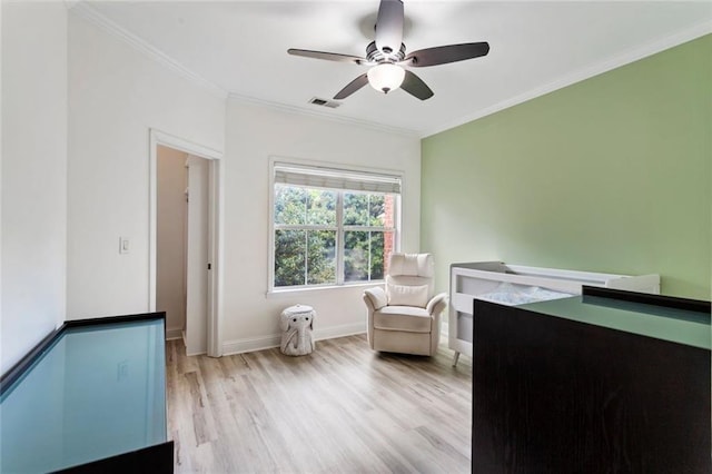 sitting room with light wood-type flooring, ornamental molding, and ceiling fan