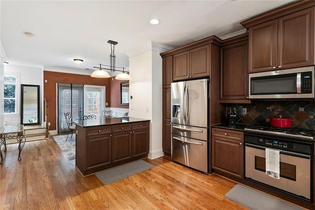 kitchen with appliances with stainless steel finishes, a peninsula, decorative backsplash, crown molding, and light wood-type flooring
