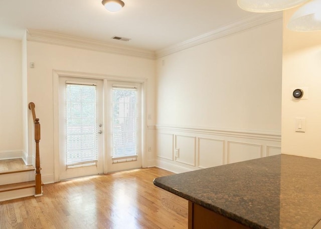 dining area with french doors, light wood-style flooring, ornamental molding, and stairway