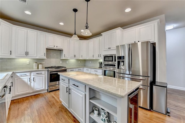 kitchen featuring stainless steel appliances, a center island, white cabinetry, and light wood-style flooring