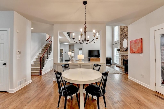 dining space with light wood-style floors, stairs, visible vents, and a fireplace