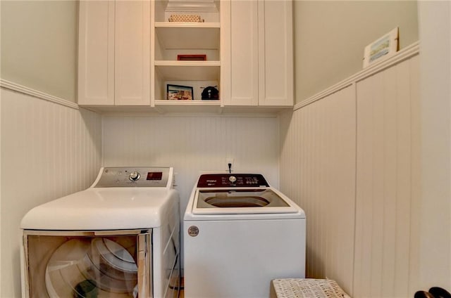 laundry room with a wainscoted wall, independent washer and dryer, and cabinet space