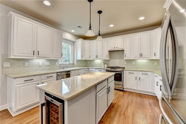 kitchen featuring beverage cooler, visible vents, appliances with stainless steel finishes, a center island, and a sink