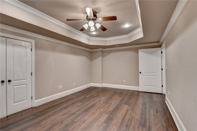 spare room featuring baseboards, wood finished floors, a tray ceiling, crown molding, and recessed lighting