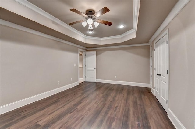 interior space with baseboards, dark wood finished floors, a raised ceiling, crown molding, and recessed lighting