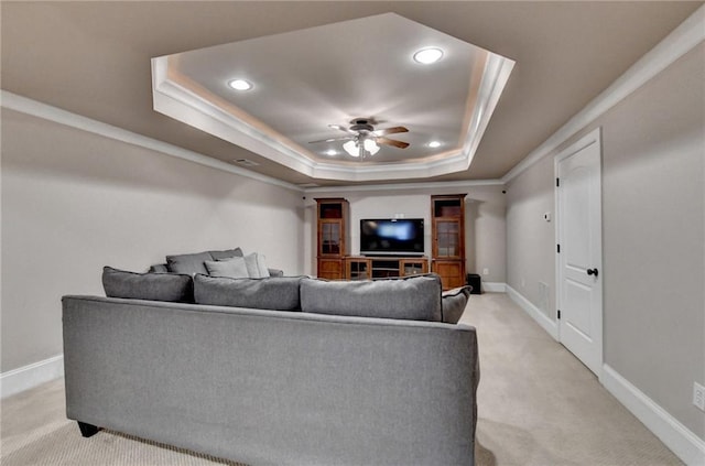 interior space featuring light carpet, a ceiling fan, baseboards, ornamental molding, and a raised ceiling