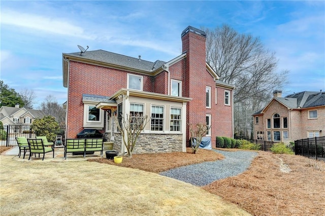 back of property featuring brick siding, a patio, a chimney, fence, and stone siding