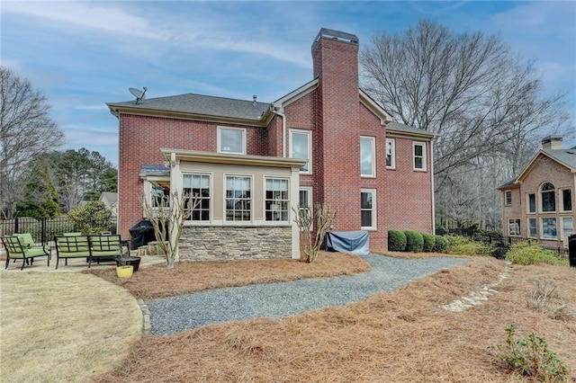 back of house featuring a patio area, a chimney, fence, and brick siding