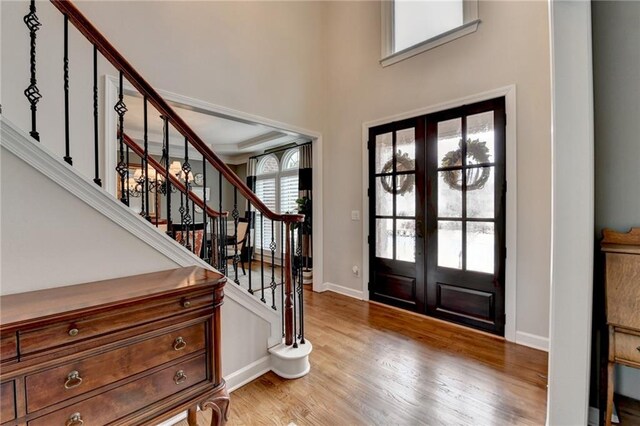 entryway with french doors, light wood-style flooring, baseboards, and stairs