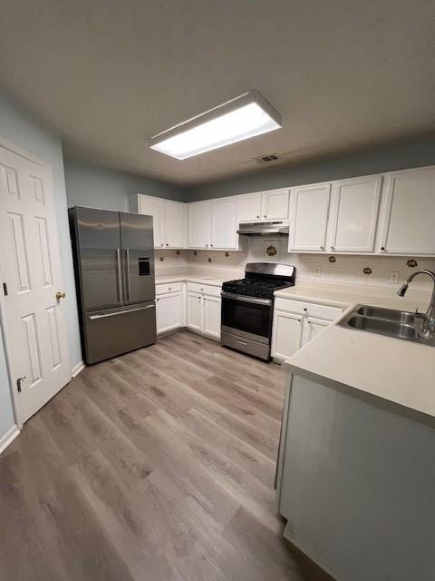 kitchen with sink, white cabinets, stainless steel appliances, and light wood-type flooring