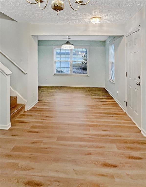 unfurnished dining area featuring a textured ceiling and light wood-type flooring