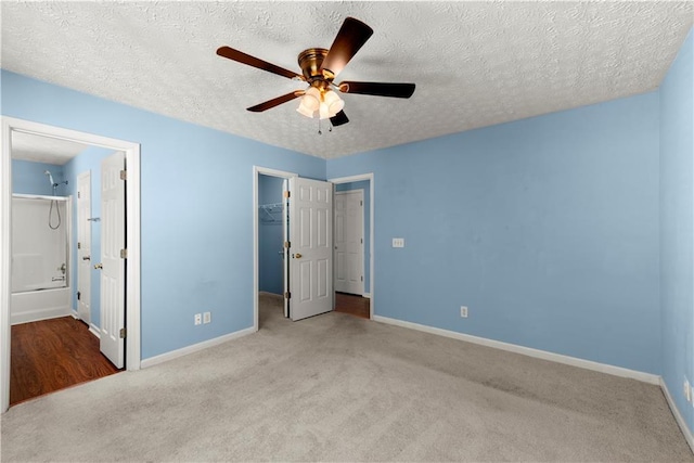 unfurnished bedroom featuring light carpet, a textured ceiling, ceiling fan, a spacious closet, and a closet