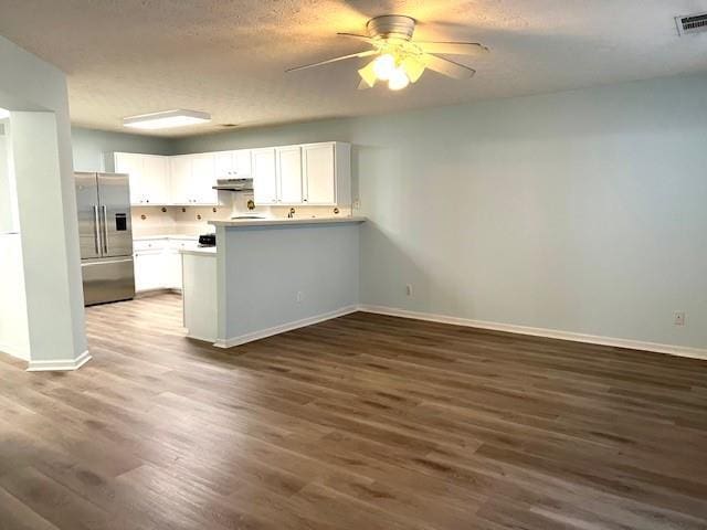 kitchen with white cabinets, stainless steel refrigerator with ice dispenser, dark hardwood / wood-style floors, ceiling fan, and kitchen peninsula