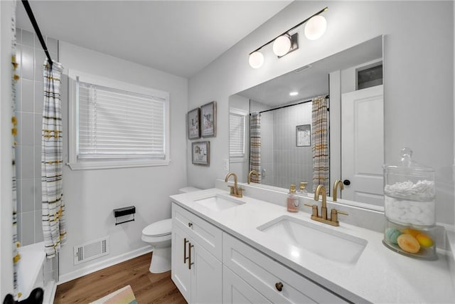 bathroom featuring visible vents, toilet, wood finished floors, and a sink