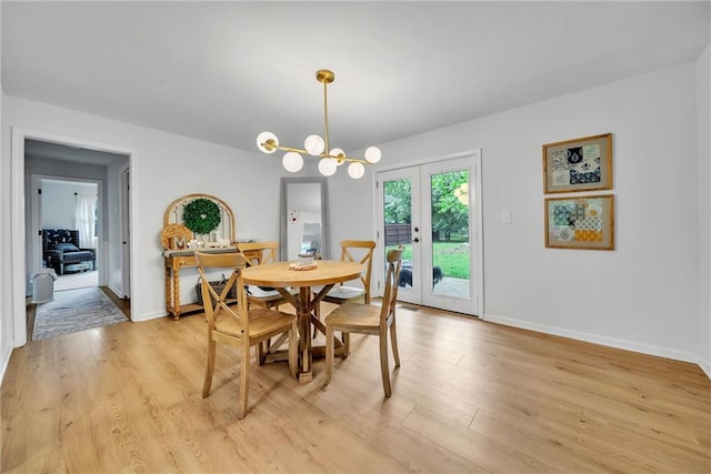 dining space featuring baseboards, a chandelier, and light wood finished floors