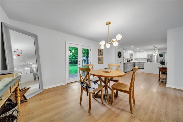 dining space featuring light wood finished floors, a chandelier, french doors, and baseboards