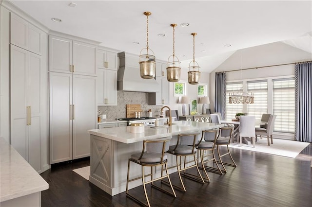 2110 Timball Rd NW, Atlanta, GA 30318 - kitchen featuring premium range hood, decorative backsplash, dark wood-style floors, a breakfast bar, and a center island with sink