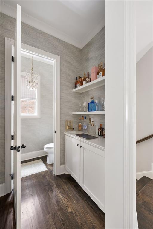 2110 Timball Rd NW, Atlanta, GA 30318 - indoor bar featuring a chandelier, baseboards, crown molding, and dark wood-style flooring