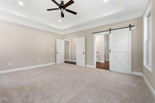 unfurnished bedroom with crown molding, a barn door, a raised ceiling, carpet, and recessed lighting