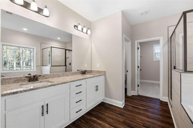 bathroom featuring visible vents, a sink, wood finished floors, and a shower stall