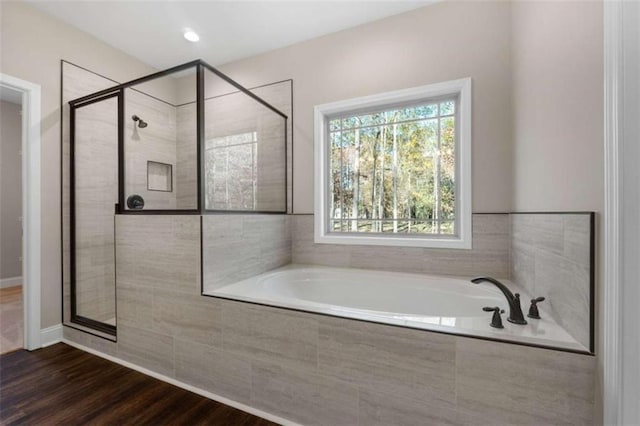 bathroom with wood finished floors, a garden tub, and a stall shower