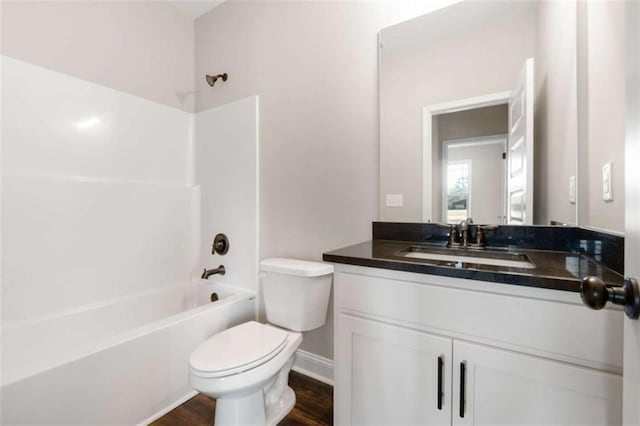 full bath featuring vanity, wood finished floors, toilet, baseboards, and washtub / shower combination