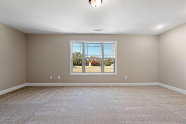 spare room with baseboards, visible vents, and light colored carpet