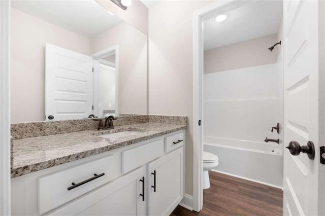 full bath with toilet, tub / shower combination, wood finished floors, and vanity