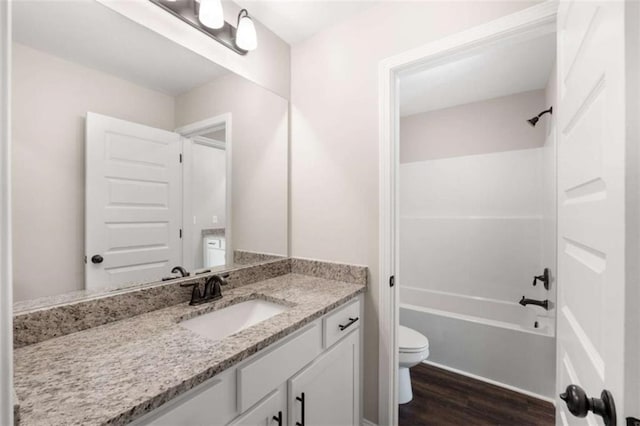 bathroom featuring toilet, bathing tub / shower combination, wood finished floors, and vanity