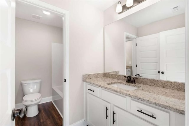 bathroom featuring vanity, toilet, baseboards, wood finished floors, and visible vents