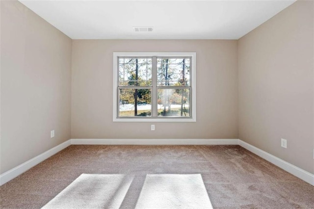 carpeted spare room featuring baseboards and visible vents