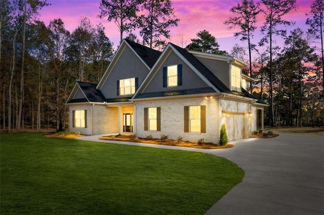 modern farmhouse with an attached garage, brick siding, stucco siding, concrete driveway, and a lawn